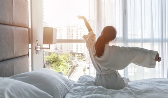 朝日を浴び起床する女性